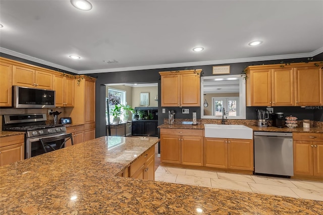 kitchen featuring recessed lighting, stainless steel appliances, a sink, ornamental molding, and dark stone countertops