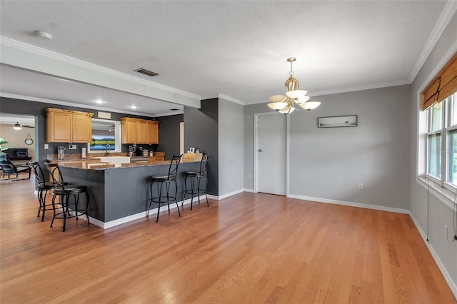 kitchen featuring a breakfast bar, light wood-type flooring, crown molding, and an inviting chandelier