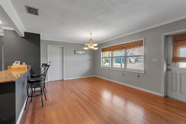 dining area with baseboards, light wood-style flooring, visible vents, and a textured ceiling