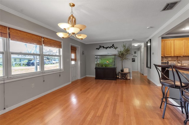 entrance foyer featuring crown molding, a notable chandelier, light wood finished floors, visible vents, and baseboards