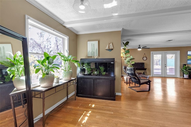 interior space with a textured ceiling, beam ceiling, a wealth of natural light, and light wood-style floors