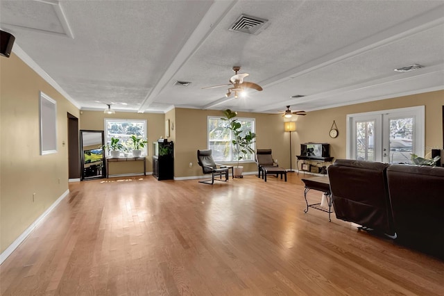 living room with light wood-type flooring, french doors, visible vents, and a textured ceiling