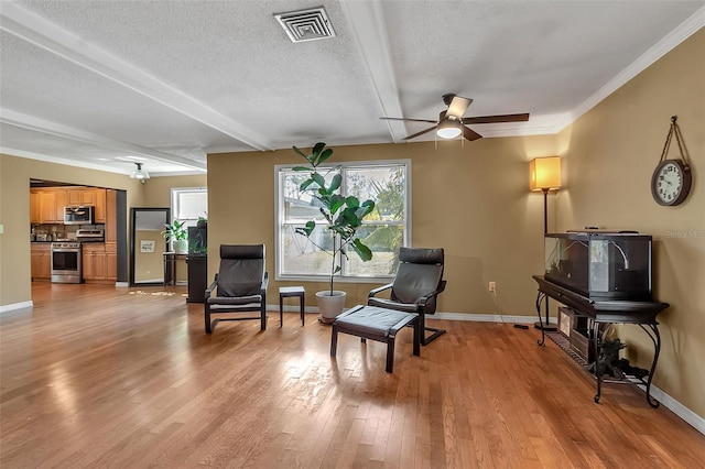 sitting room featuring light wood finished floors, baseboards, visible vents, ceiling fan, and a textured ceiling