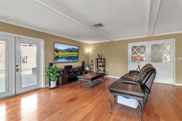 living room with light wood finished floors, baseboards, visible vents, beamed ceiling, and a textured ceiling