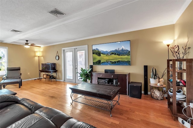 living area featuring a healthy amount of sunlight, light wood-style floors, visible vents, and a textured ceiling