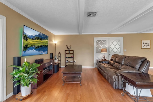 living room with a textured ceiling, light wood-style flooring, visible vents, baseboards, and beamed ceiling