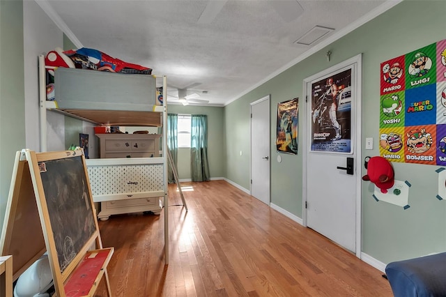 bedroom featuring visible vents, baseboards, ceiling fan, wood finished floors, and crown molding