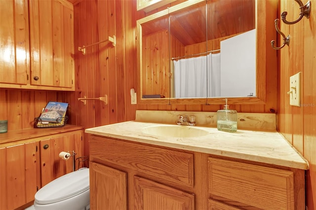 bathroom with wooden walls, a shower with shower curtain, vanity, and toilet