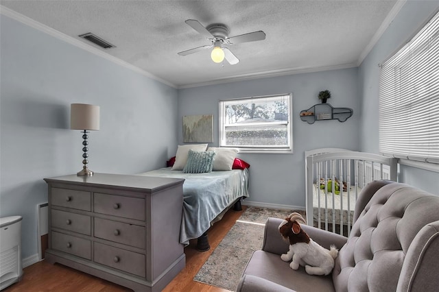 bedroom featuring ornamental molding, visible vents, a textured ceiling, and wood finished floors