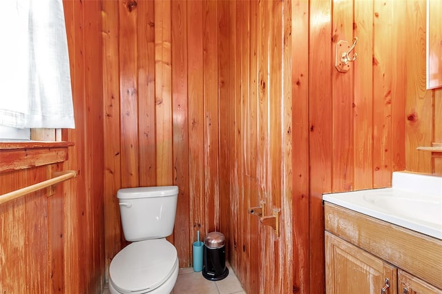 bathroom with wooden walls, tile patterned flooring, vanity, and toilet