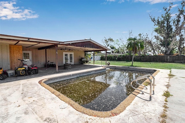 view of swimming pool featuring a fenced backyard, french doors, a lawn, a fenced in pool, and a patio area