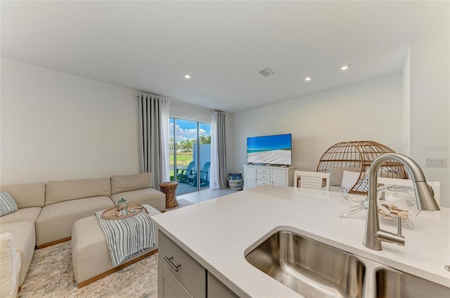 kitchen with light countertops, open floor plan, visible vents, and a sink