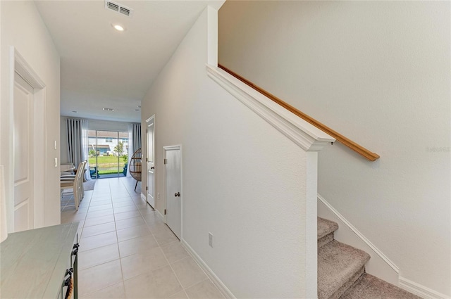 corridor with stairs, light tile patterned floors, visible vents, and baseboards