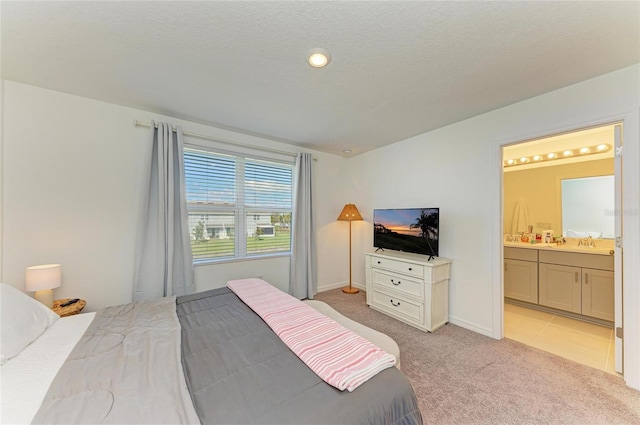 bedroom featuring ensuite bathroom, a textured ceiling, a sink, and light colored carpet