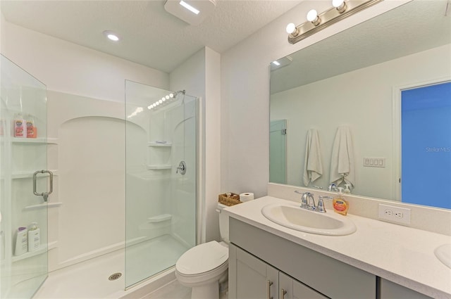 full bathroom with double vanity, toilet, a stall shower, a sink, and a textured ceiling