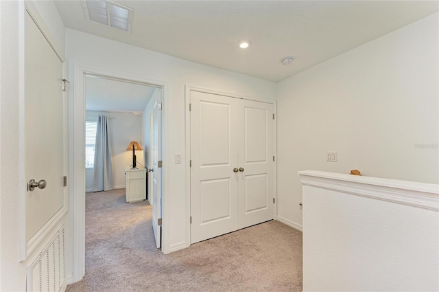 hall featuring light colored carpet, visible vents, and baseboards