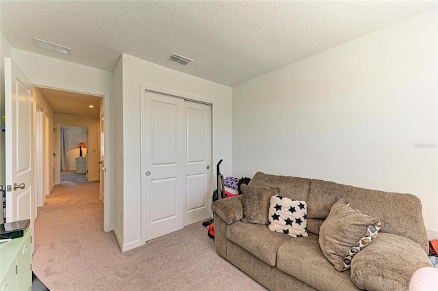 living area featuring a textured ceiling, visible vents, and light colored carpet