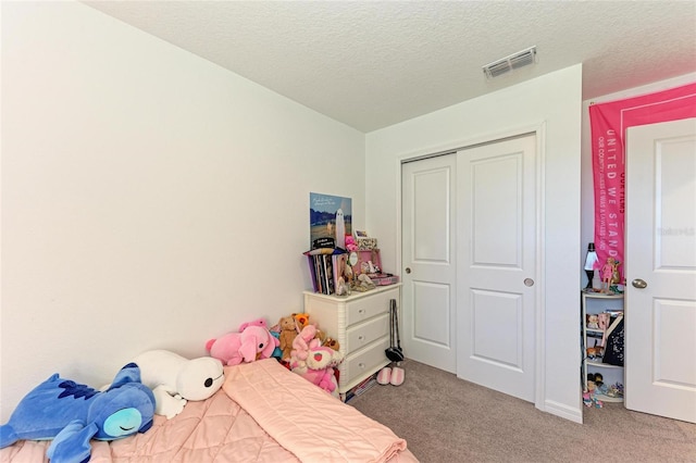 carpeted bedroom featuring a closet, visible vents, and a textured ceiling