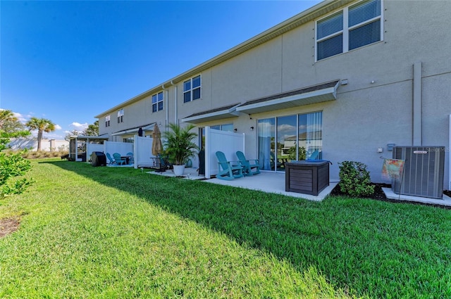 rear view of house featuring central air condition unit, a yard, a patio area, and stucco siding