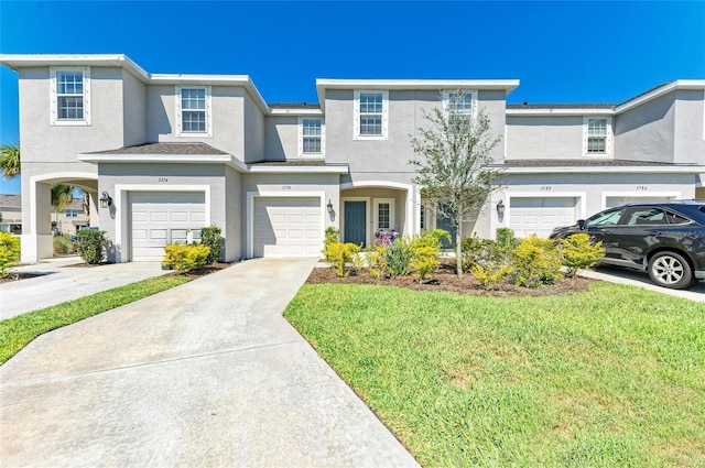 view of property with a front yard, driveway, an attached garage, and stucco siding