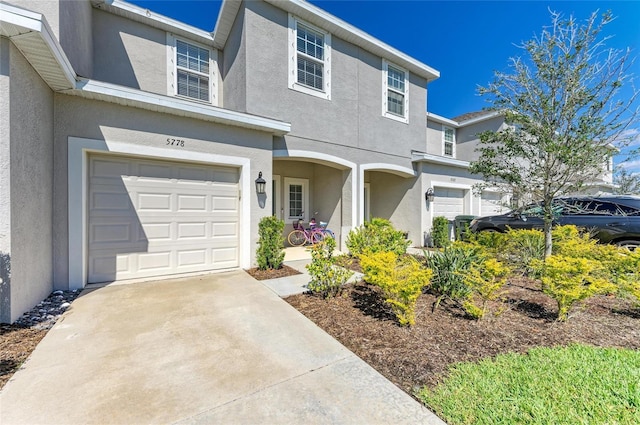 traditional-style home with a garage, concrete driveway, and stucco siding