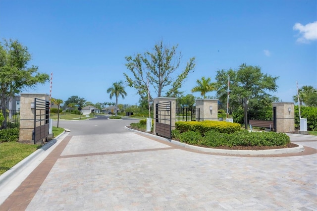 view of street with a gate, curbs, and a gated entry