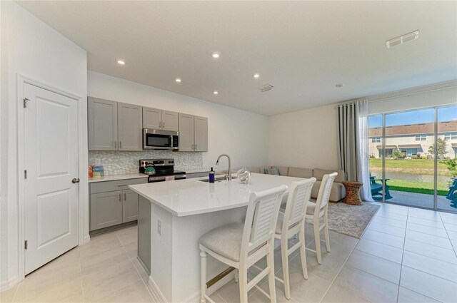 kitchen featuring gray cabinets, visible vents, backsplash, appliances with stainless steel finishes, and a sink