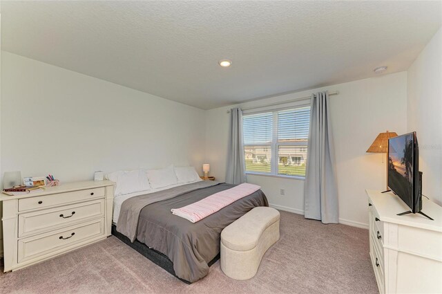 bedroom with a textured ceiling, baseboards, and light colored carpet