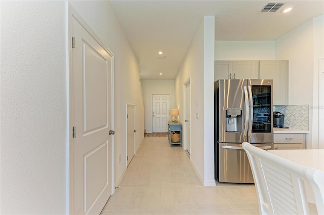 hallway with recessed lighting, visible vents, baseboards, and light tile patterned floors