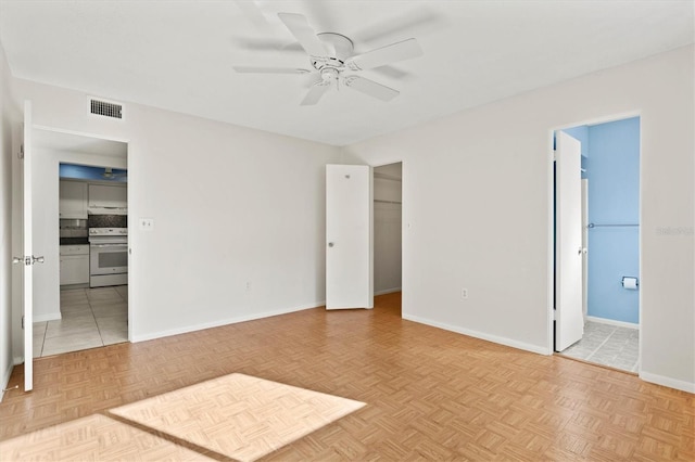 unfurnished bedroom with ceiling fan, visible vents, baseboards, a spacious closet, and ensuite bath