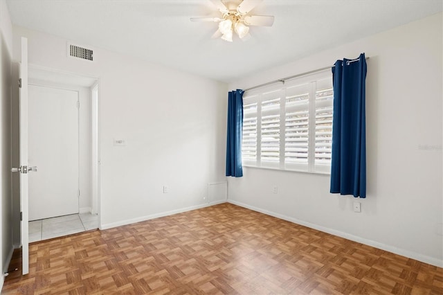 empty room featuring baseboards, visible vents, and ceiling fan