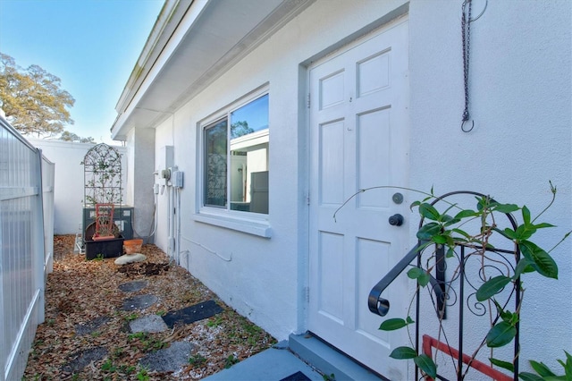 view of side of home featuring fence, central AC unit, and stucco siding