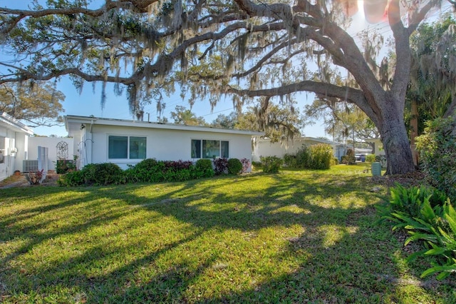 view of front of house featuring central AC unit, a front lawn, and stucco siding