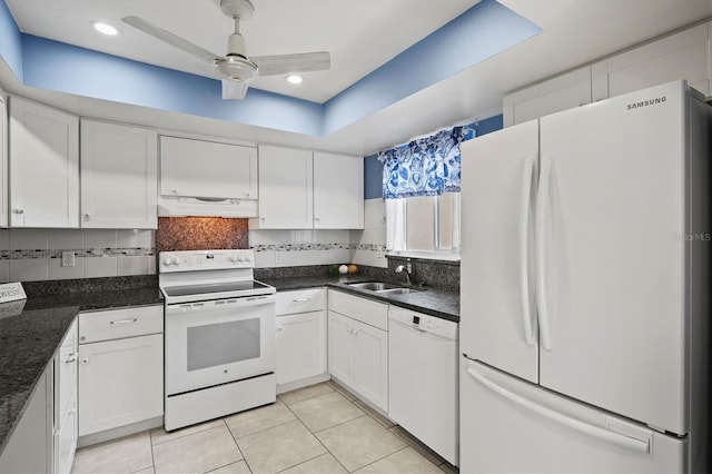 kitchen with backsplash, white cabinetry, a sink, white appliances, and under cabinet range hood