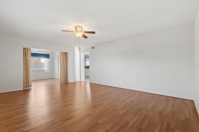 unfurnished room with ceiling fan, wood finished floors, and visible vents