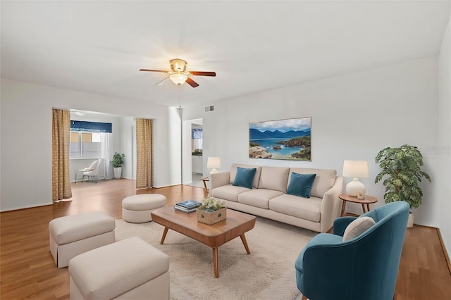 living room with a ceiling fan, visible vents, and wood finished floors