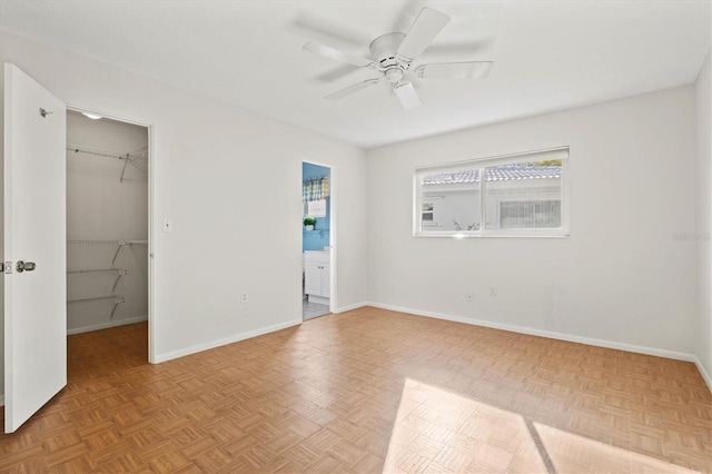 unfurnished bedroom featuring a walk in closet, a closet, ensuite bath, and baseboards