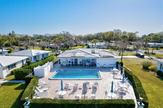 community pool with a yard, a patio area, and fence