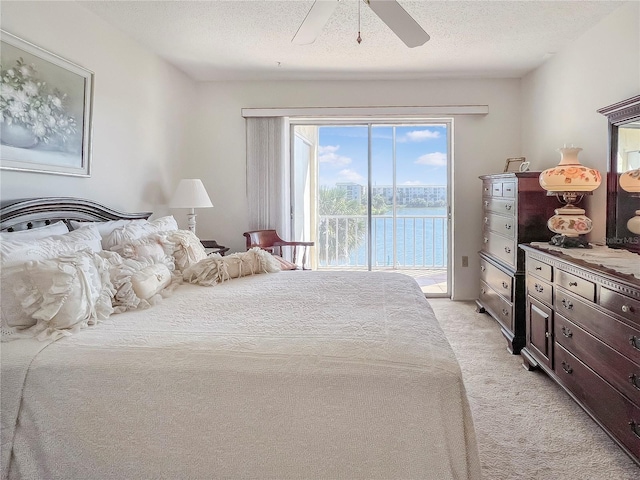 bedroom with light colored carpet, a water view, ceiling fan, a textured ceiling, and access to outside