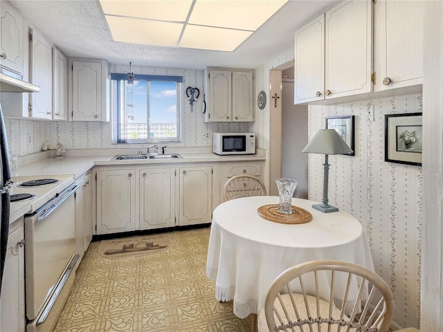 kitchen with white appliances, wallpapered walls, light countertops, light floors, and a sink