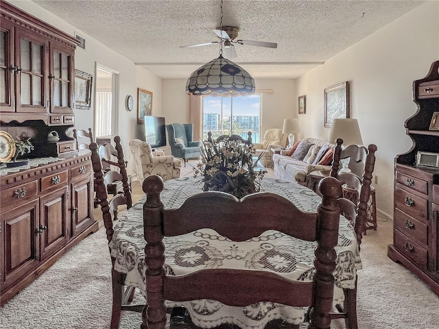 dining area with light colored carpet, ceiling fan, and a textured ceiling