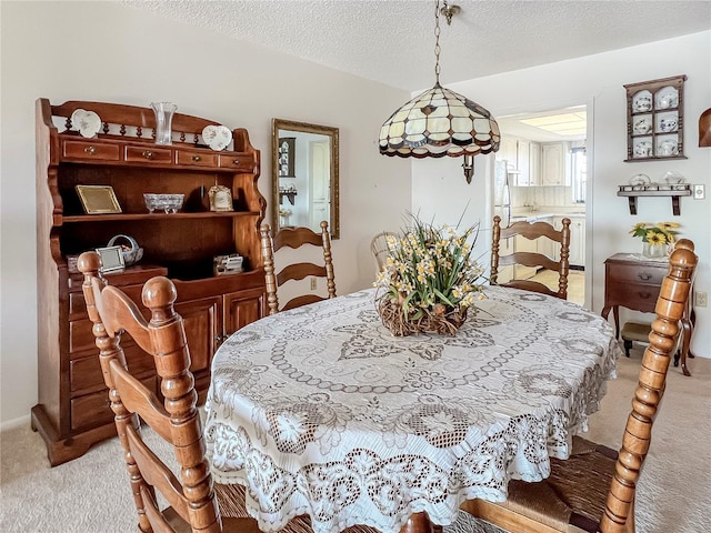 dining space featuring light colored carpet and a textured ceiling