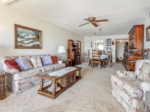 living area featuring ceiling fan, a textured ceiling, and light colored carpet