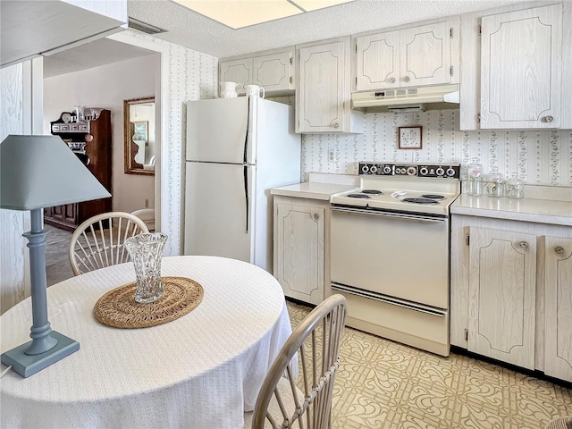 kitchen with a textured ceiling, light countertops, white appliances, and under cabinet range hood