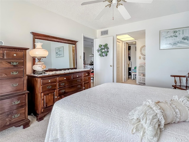 bedroom with light carpet, ceiling fan, a textured ceiling, and visible vents