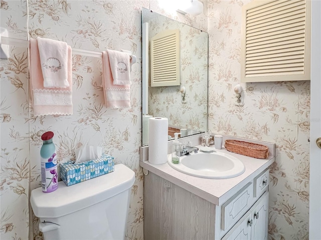 bathroom featuring vanity, toilet, and wallpapered walls