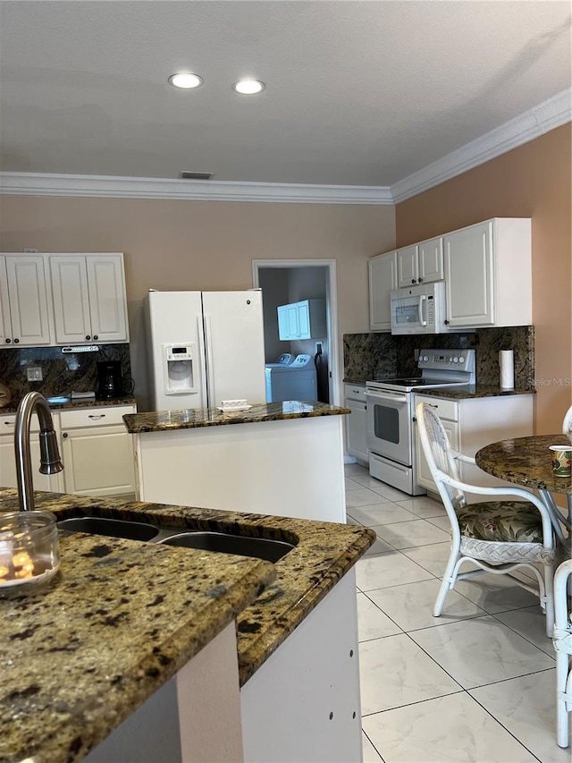 kitchen featuring ornamental molding, dark stone counters, a sink, washer and dryer, and white appliances