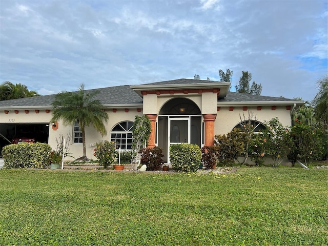 view of front of property featuring a shingled roof, a front yard, and stucco siding