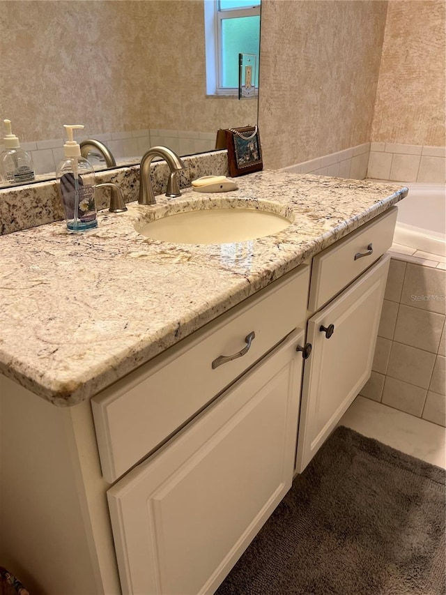 full bath with wallpapered walls, tile patterned flooring, a bathing tub, and vanity