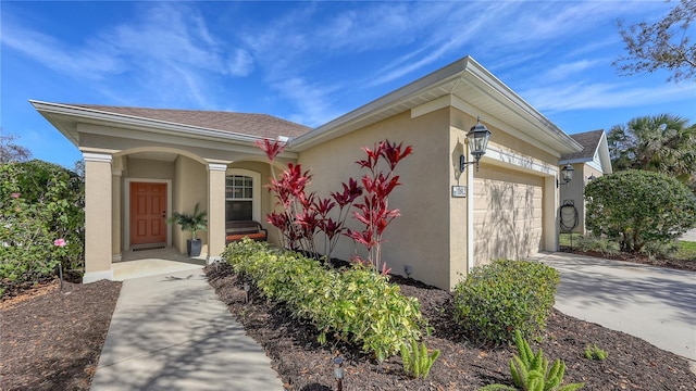 exterior space with concrete driveway, covered porch, an attached garage, and stucco siding